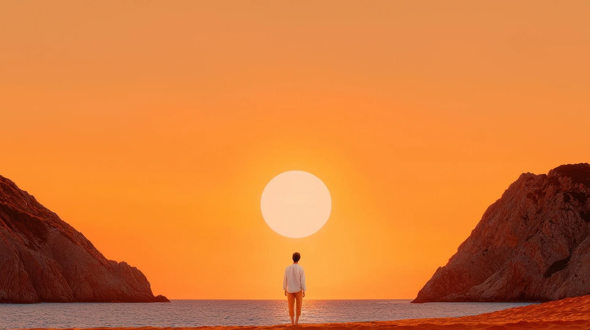 Una persona in controluce guarda il sole all'orizzonte tra due scogliere, sulla battigia