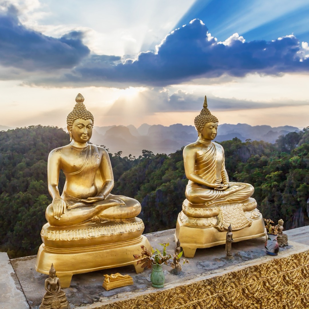 Statue del Buddha dorate al tramonto su una vetta panoramica