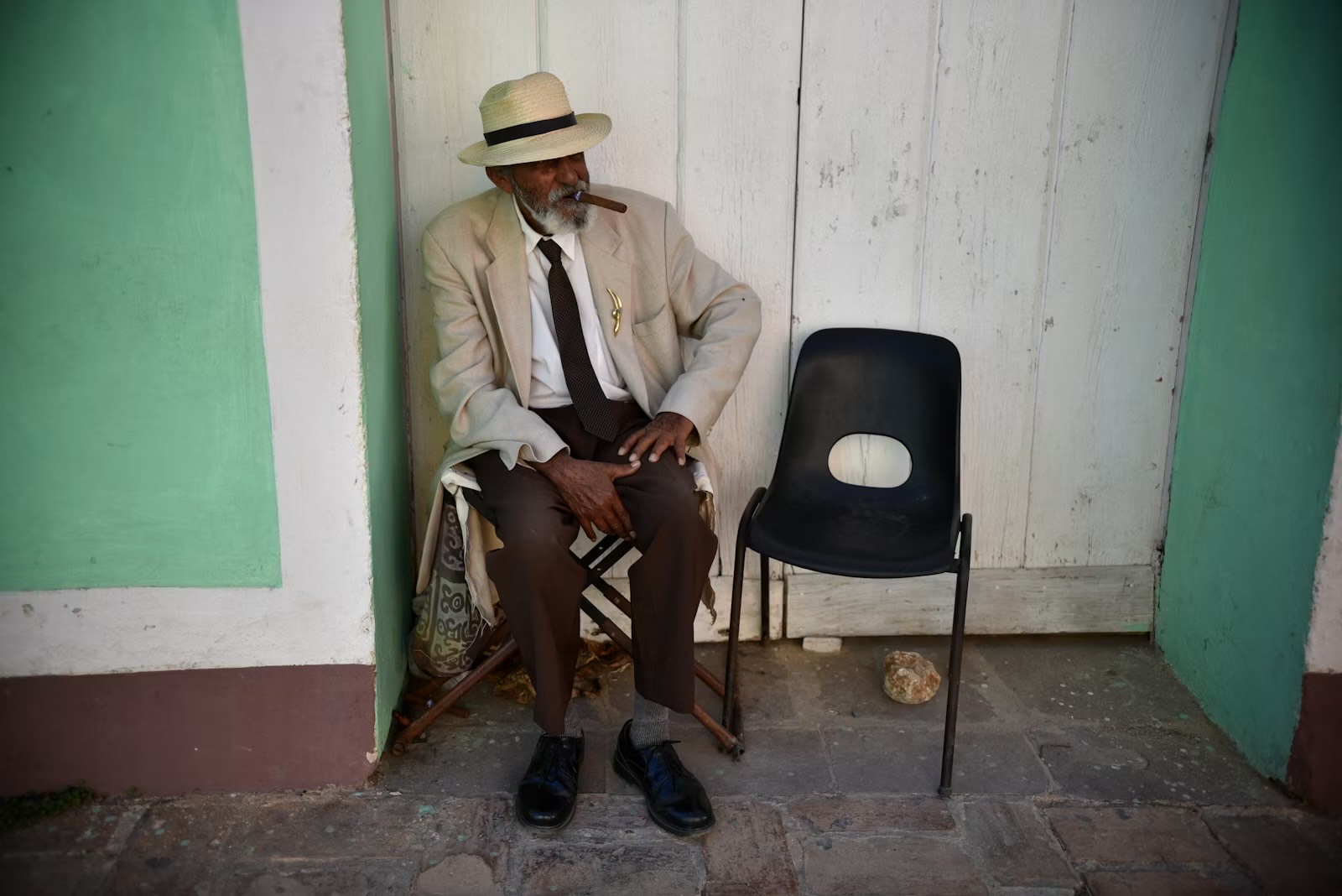Uomo in abito bianco seduto in una via di Trinidad